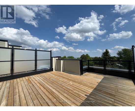 A wooden deck with a glass railing and a hot tub on a sunny day.