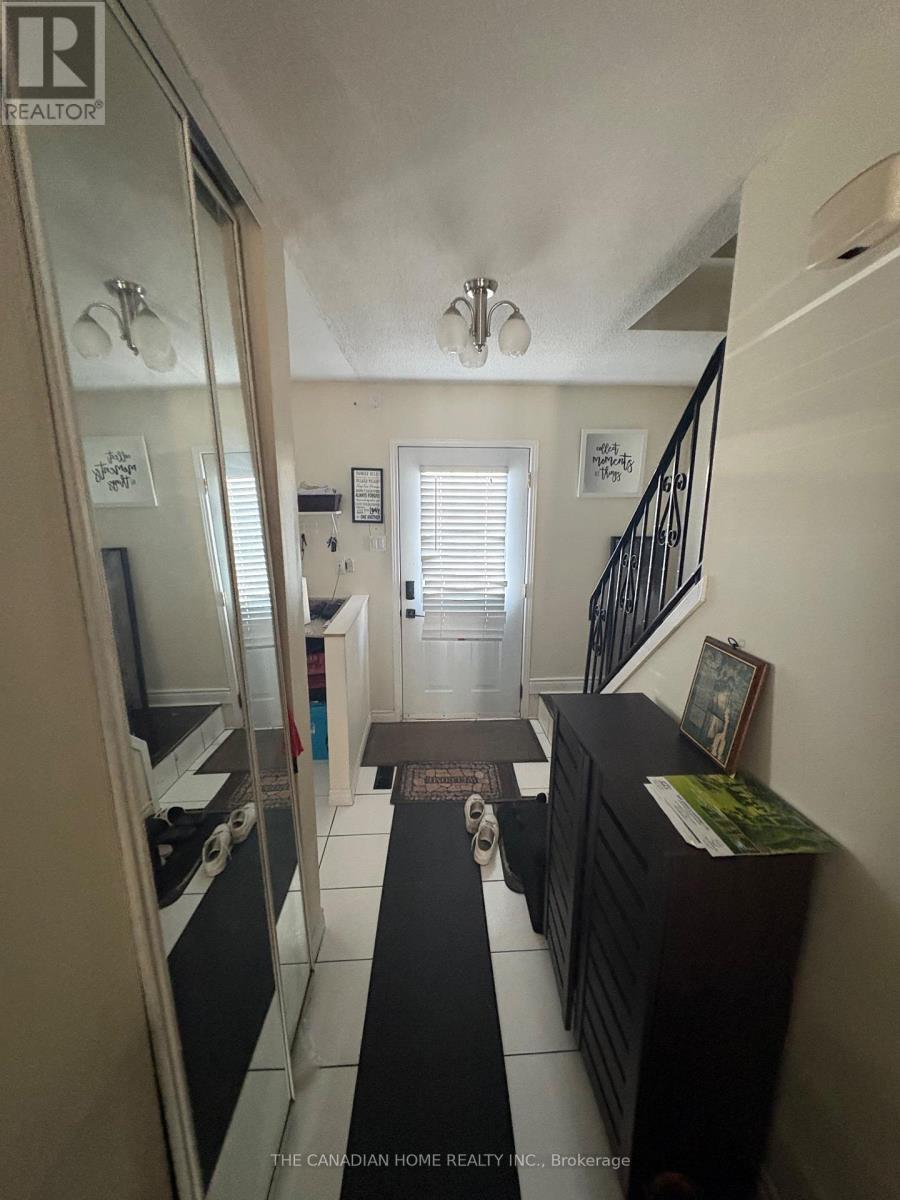 A hallway with a black and white floor, a staircase, and a mirror on the left side.