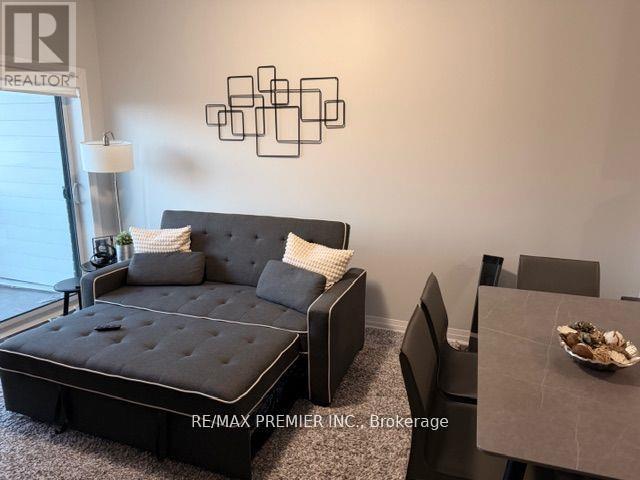 A bedroom with a black bed and a grey sofa.