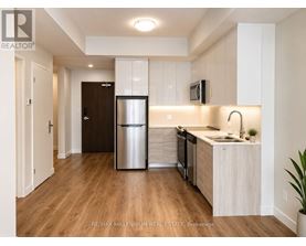 A kitchen with a refrigerator, sink, and cabinets.