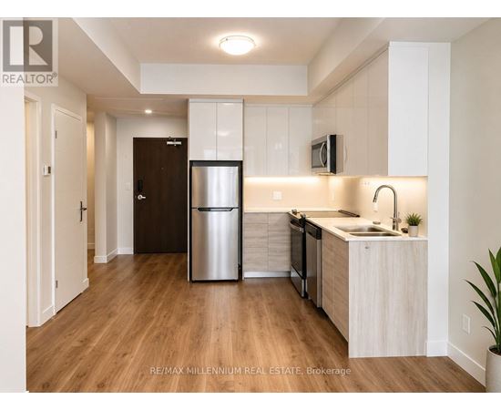 A kitchen with a refrigerator, sink, and cabinets.