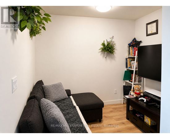 A living room with a couch, a television, and a plant on the wall.