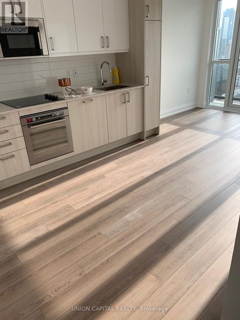 A kitchen with wooden floors and white cabinets.