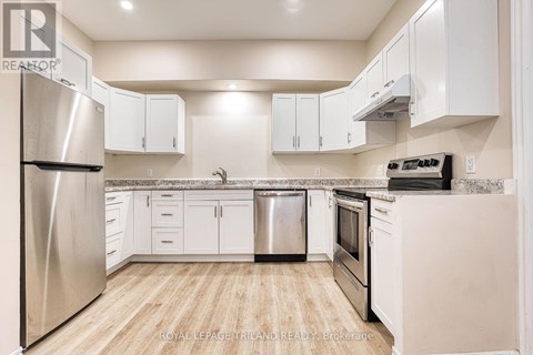 A kitchen with white cabinets and a stainless steel refrigerator.
