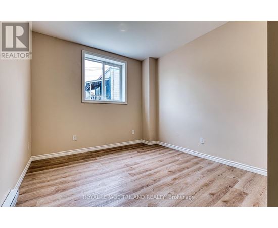 A room with wooden flooring and a window showing a building outside.