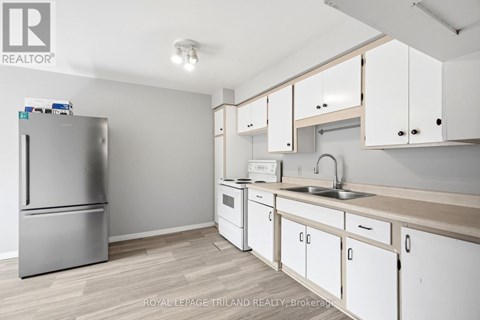 A kitchen with white cabinets and a stainless steel refrigerator.