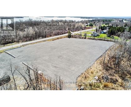 A large, empty parking lot sits in the foreground of a rural landscape.