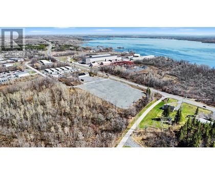 A real estate company is advertising a property with an aerial view of a parking lot, buildings, and a body of water.