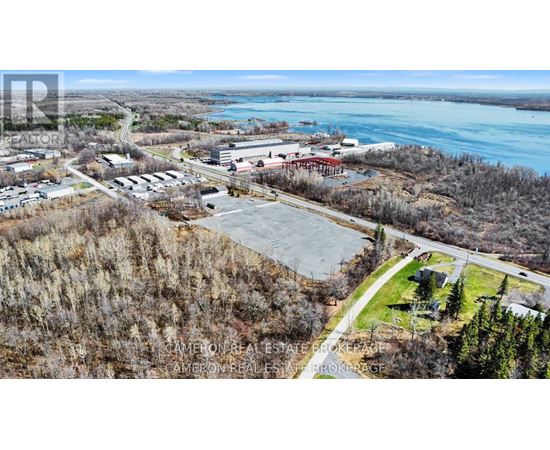 A real estate company is advertising a property with an aerial view of a parking lot, buildings, and a body of water.