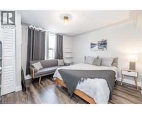 A bedroom with a bed, a bench, and a nightstand.