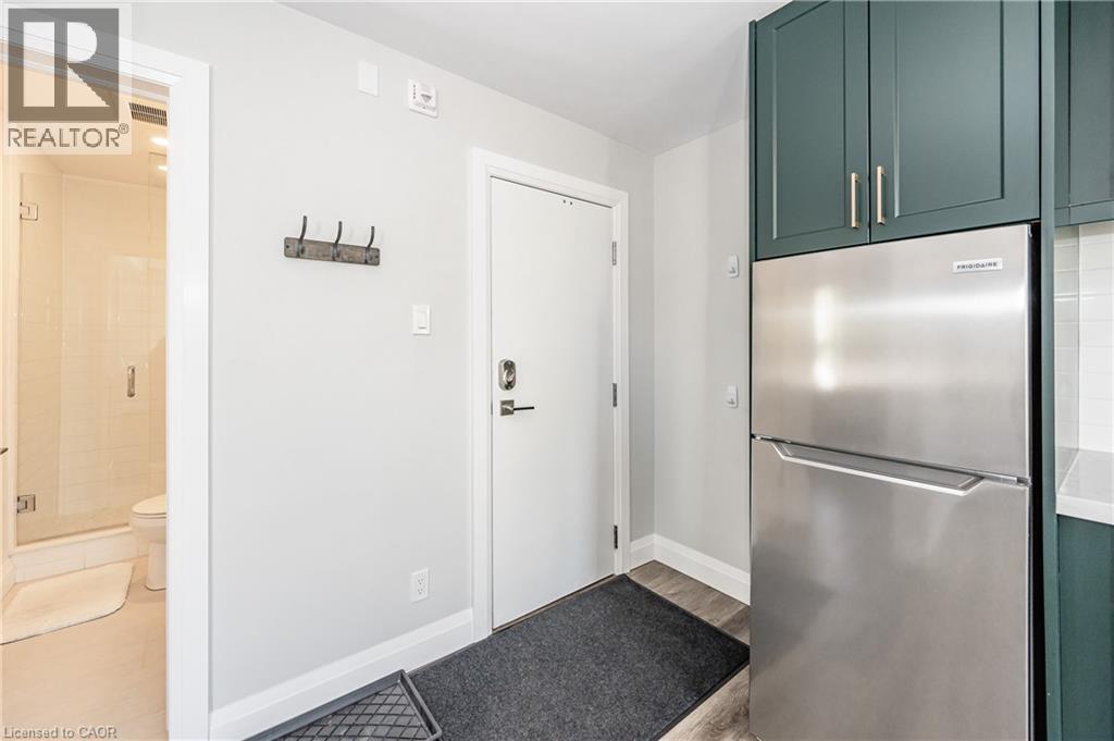 A kitchen with a stainless steel refrigerator and green cabinets.
