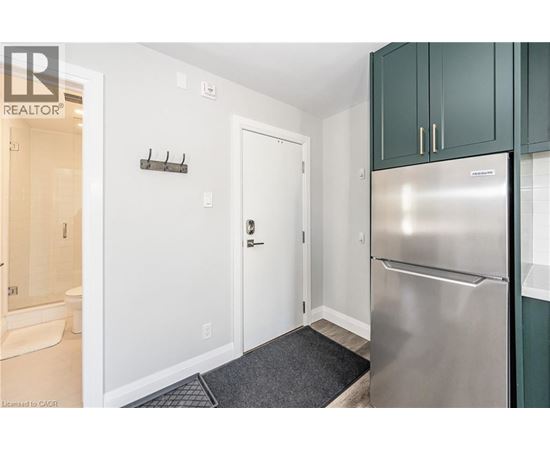 A kitchen with a stainless steel refrigerator and green cabinets.