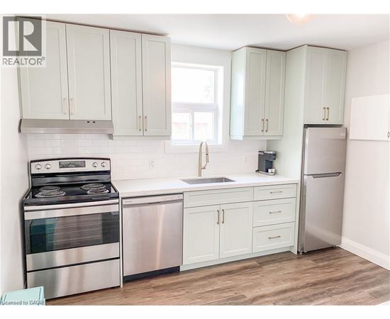 A kitchen with white cabinets and a stainless steel refrigerator.