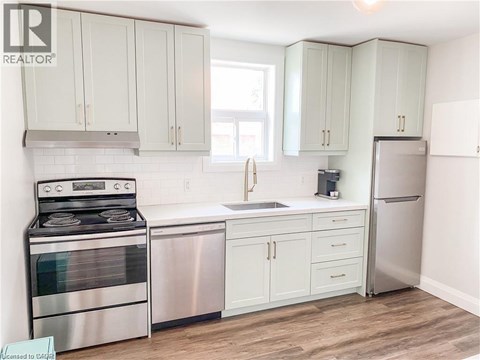 A kitchen with white cabinets and a stainless steel refrigerator.