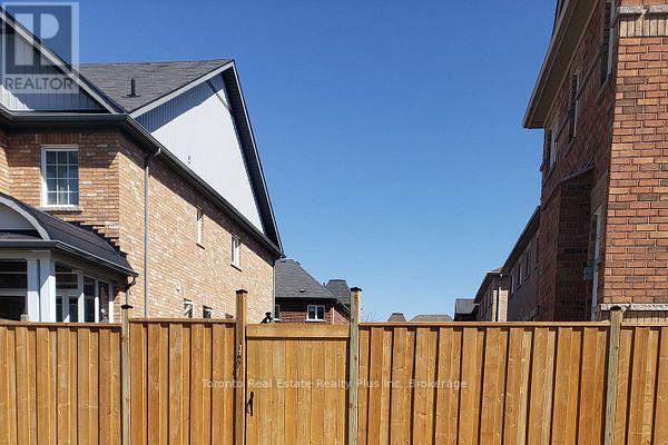 A wooden fence separates two houses.