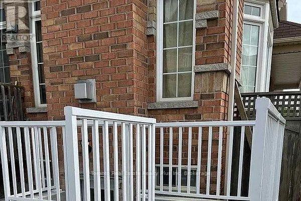 A white fence in front of a red brick building.