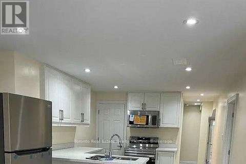 A kitchen with white cabinets and a stainless steel refrigerator.