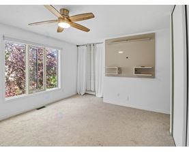 A room with a ceiling fan and a window with a view of trees.