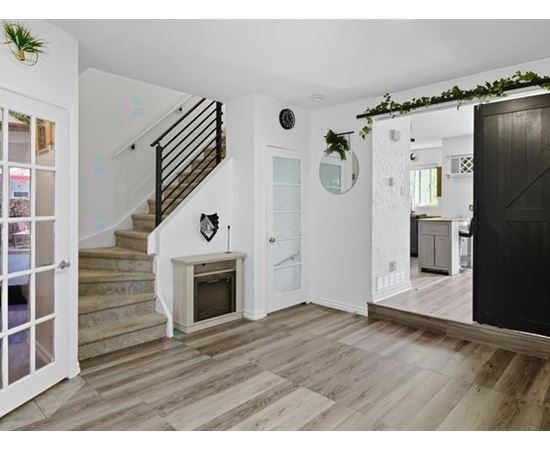 A living room with a black door and a staircase.