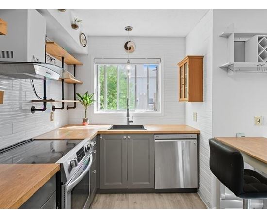 A kitchen with a wooden counter top and stainless steel appliances.