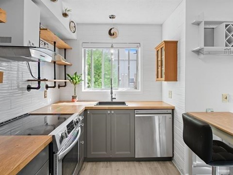 A kitchen with a wooden counter top and stainless steel appliances.