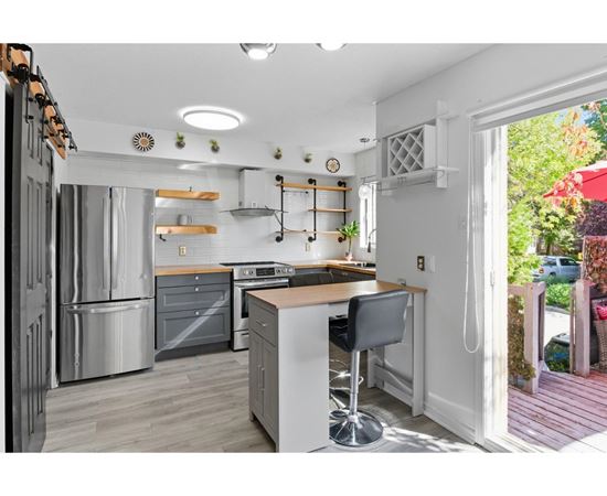 A modern kitchen with a large island and a refrigerator on the left.