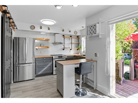 A modern kitchen with a large island and a refrigerator on the left.