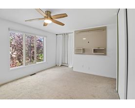 A room with a ceiling fan and a window overlooking trees.