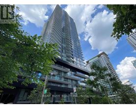 A tall building with many windows is surrounded by trees.