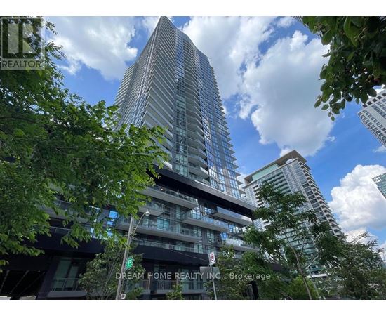 A tall building with many windows is surrounded by trees.