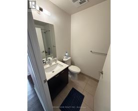 A bathroom with a toilet, sink, and mirror.