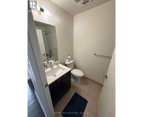 A bathroom with a toilet, sink, and mirror.