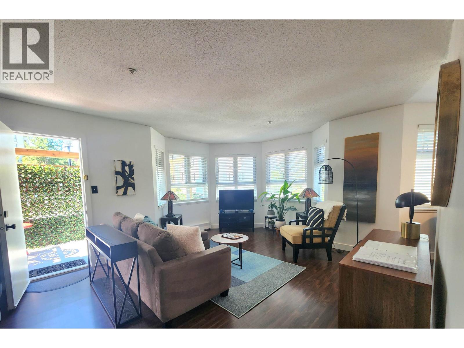 A living room with a couch, chair, and a table with a lamp on it.
