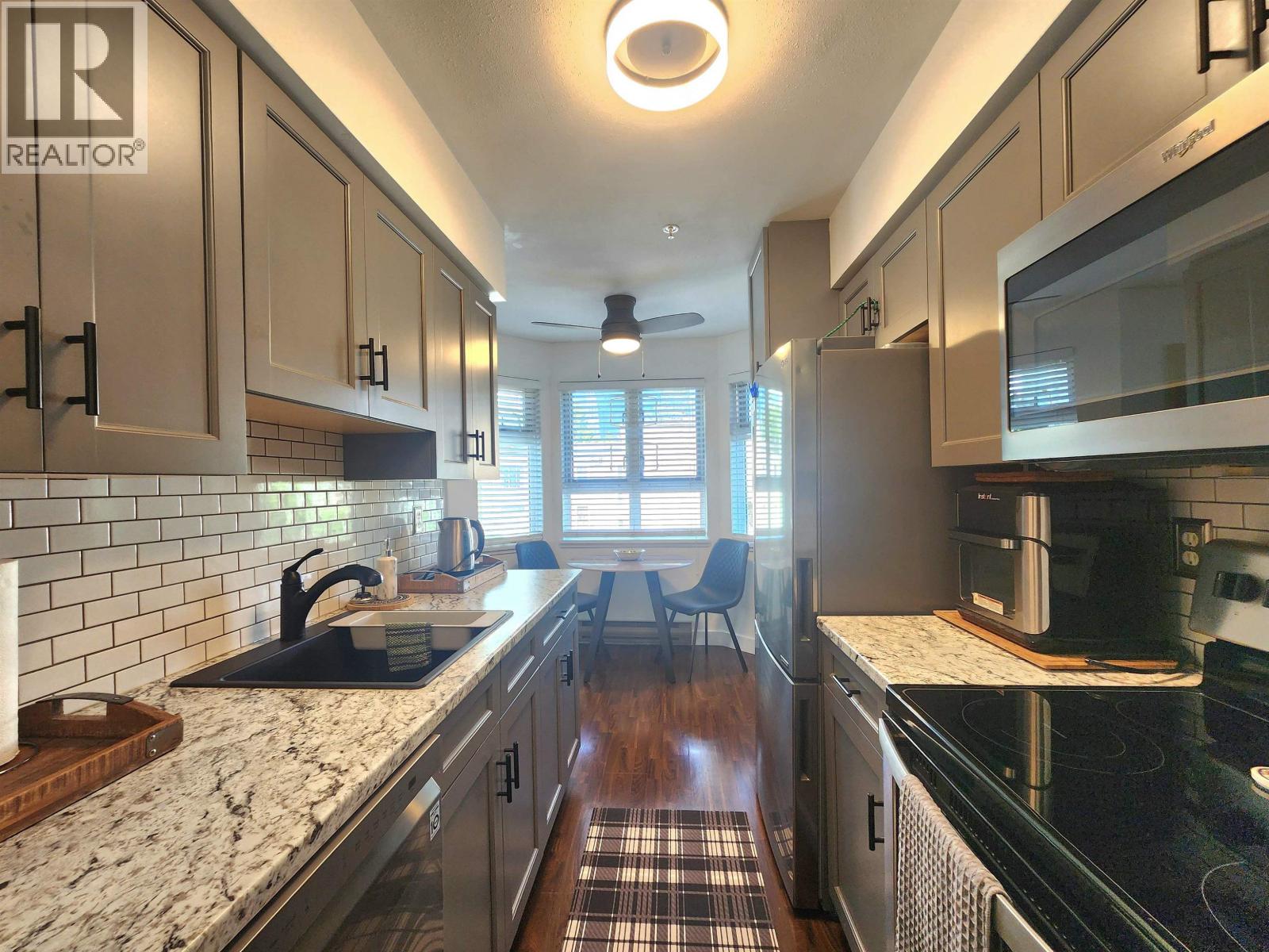 A kitchen with a black counter top and white cabinets.