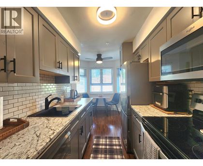 A kitchen with a black counter top and white cabinets.