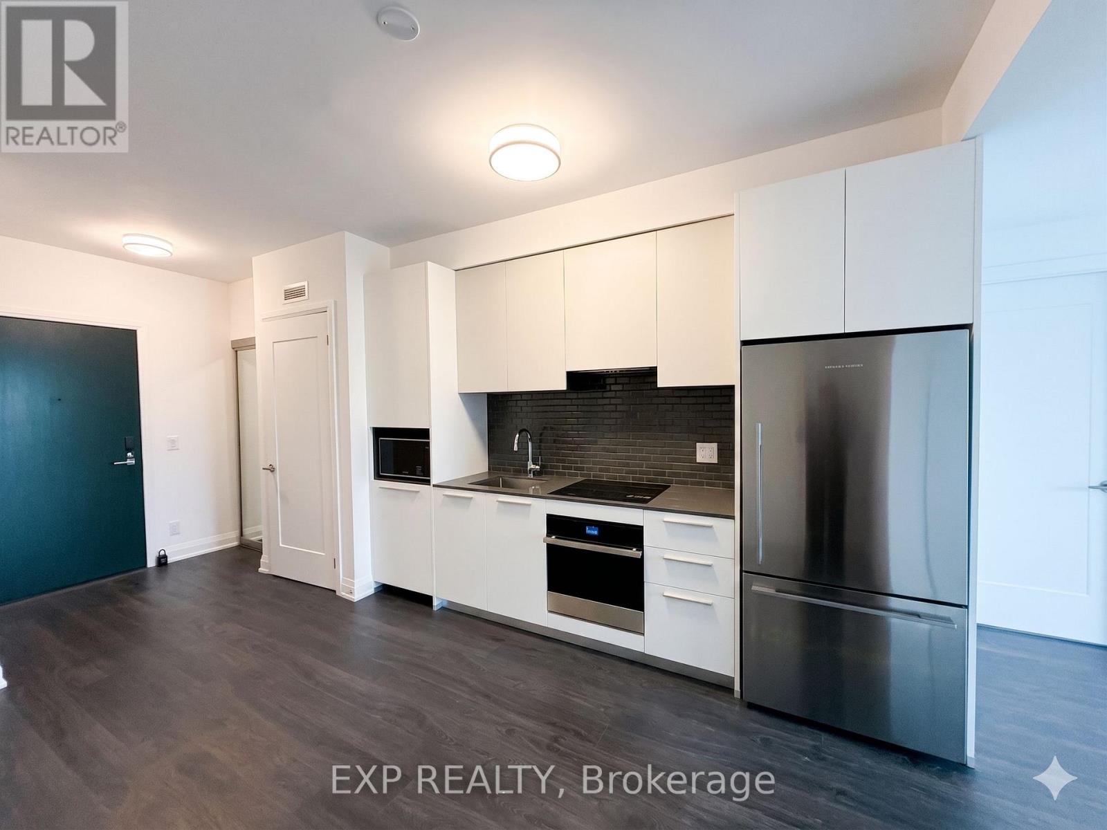 A modern kitchen with white cabinets and a stainless steel refrigerator.