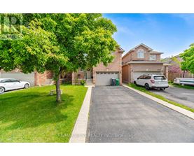 A house with a driveway and a tree in front of it.