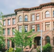 A large, old building with a lot of windows and a staircase leading to the entrance.