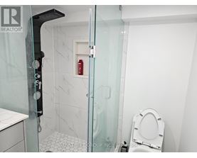A white toilet sits in a small bathroom with a glass shower door.