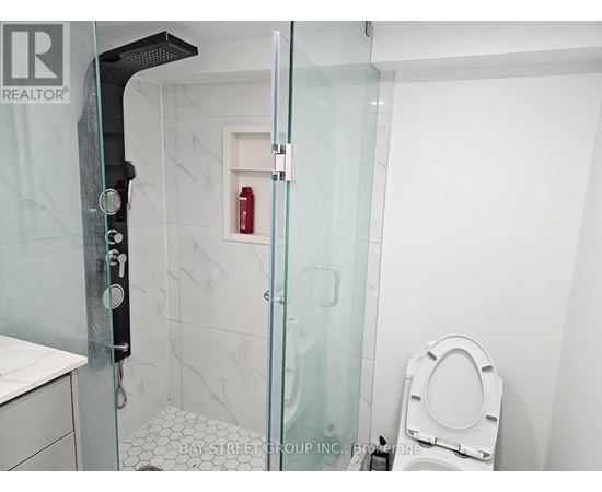 A white toilet sits in a small bathroom with a glass shower door.
