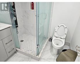 A white toilet sits in a bathroom next to a glass shower stall.