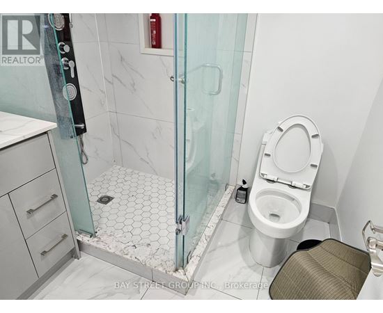 A white toilet sits in a bathroom next to a glass shower stall.
