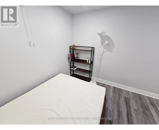 A white bed in a room with a small shelf and a lamp.