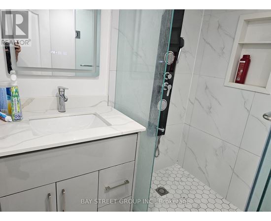 A white sink in a bathroom with a glass shower door.