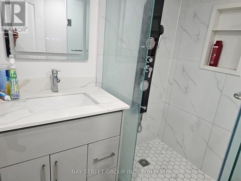A white sink in a bathroom with a glass shower door.