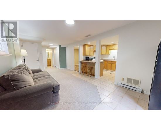 A living room with a grey couch and a kitchen area in the background.