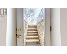 A white door with a gold handle and a set of stairs leading up to it.
