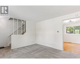 A spacious room with a staircase and a window overlooking a backyard.