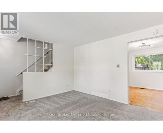 A spacious room with a staircase and a window overlooking a backyard.