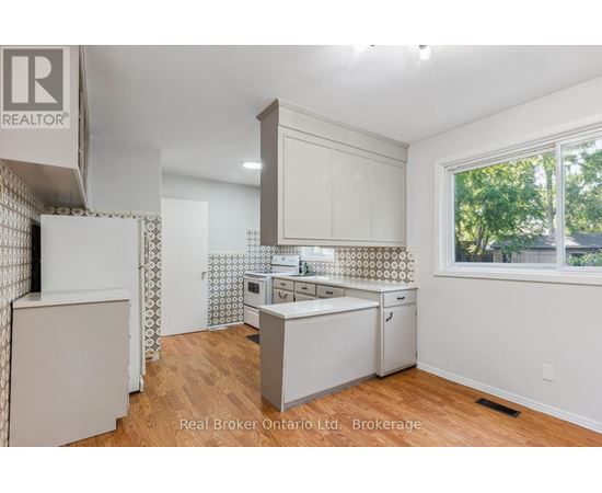 A kitchen with white cabinets and a wooden floor.